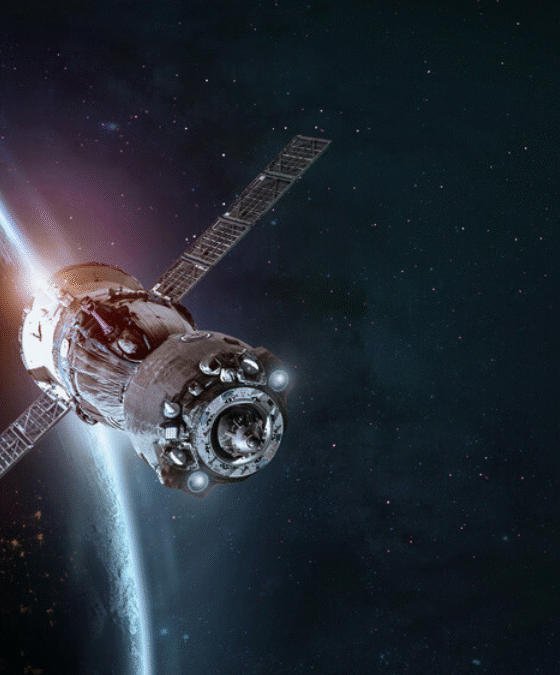 Artificial satellite orbiting Earth with visible solar panels and atmospheric glow in the background, representing advanced space technology.