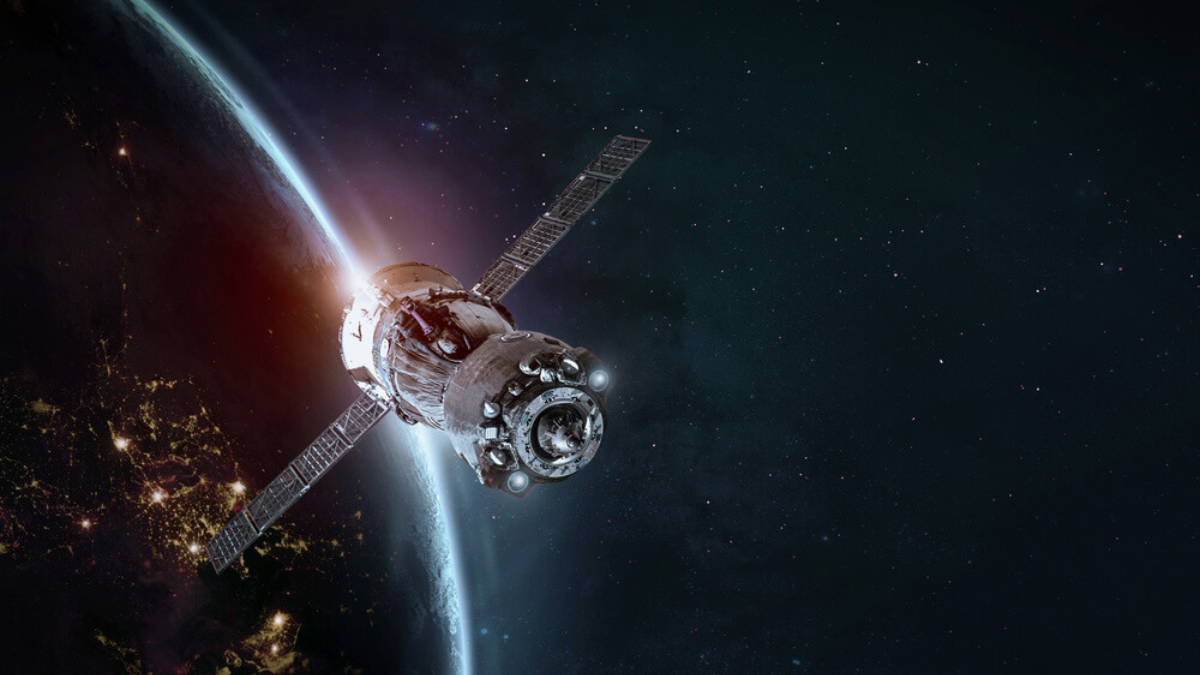 Artificial satellite orbiting Earth with visible solar panels and atmospheric glow in the background, representing advanced space technology.