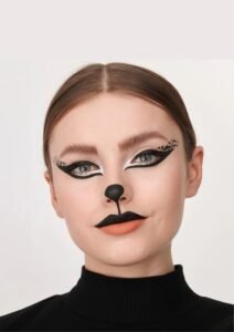 Model wearing sleek cat-eye halloween makeup design with whisker lines and dark lips.