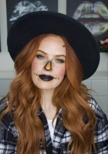 Scarecrow-inspired halloween makeup design with orange eyeshadow and stitched mouth detailing.