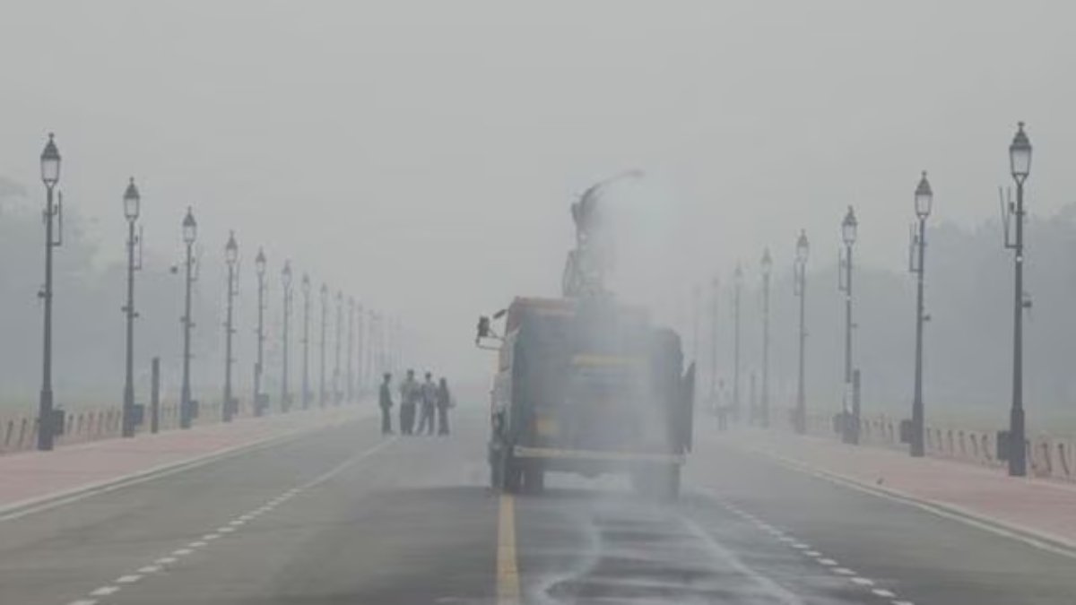 Smog covers Delhi as air quality drops, with a cleaning vehicle spraying water to reduce Delhi air pollution.