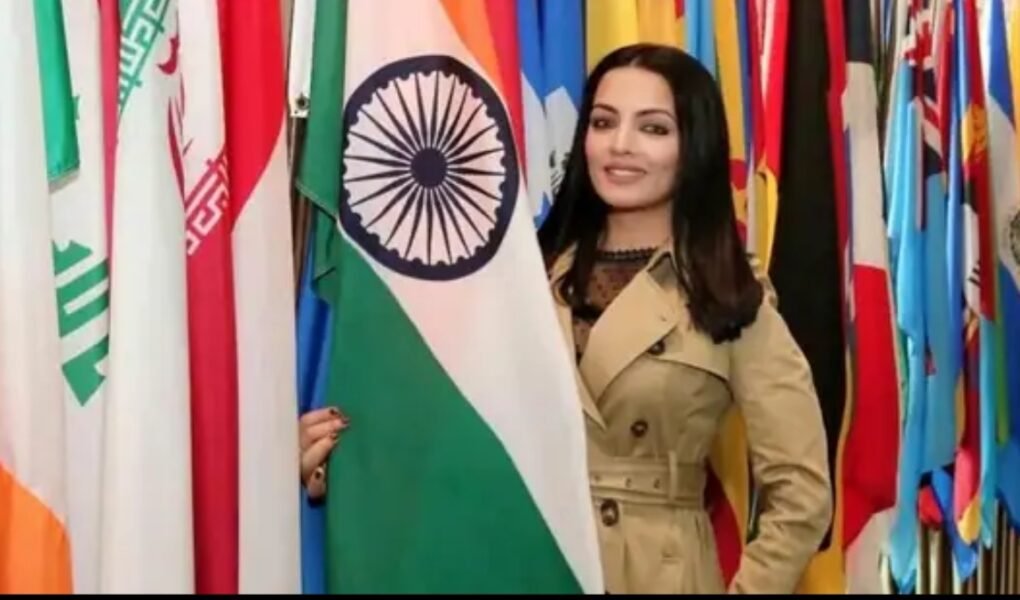 Bollywood actress Celina Jaitly standing beside Indian flag at an international event
