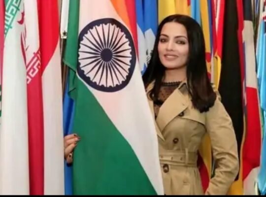 Bollywood actress Celina Jaitly standing beside Indian flag at an international event