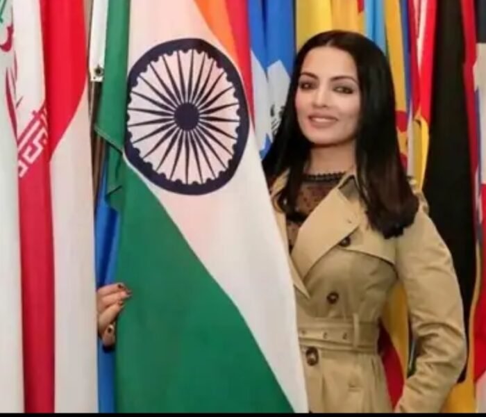 Bollywood actress Celina Jaitly standing beside Indian flag at an international event