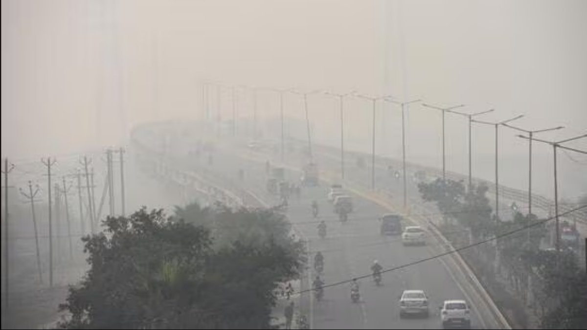 Aerial view of a city flyover or bridge covered in dense smog, highlighting severe air pollution and extremely low visibility.