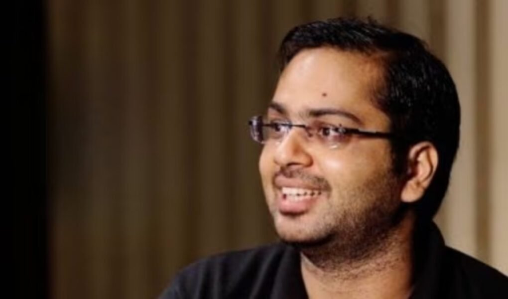 Close-up headshot of the IITian CEO, wearing glasses and a black shirt, smiling while discussing the **trending** topic of paying a high salary for a home manager.