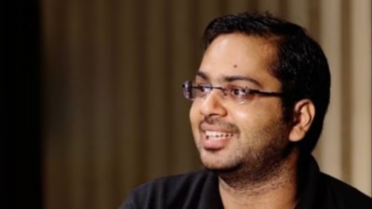 Close-up headshot of the IITian CEO, wearing glasses and a black shirt, smiling while discussing the **trending** topic of paying a high salary for a home manager.