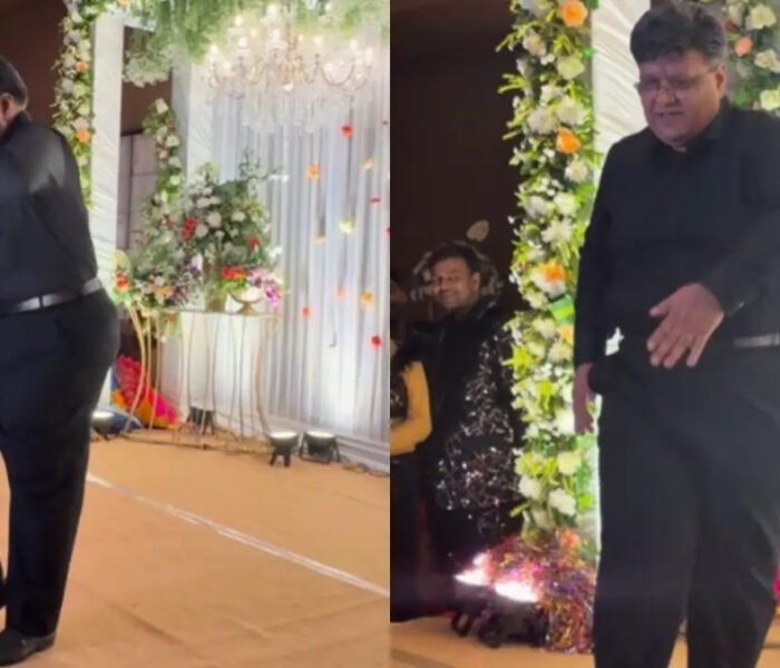An elderly father dressed in all black performing a humorous slow-motion dance on stage at his daughter's Sangeet ceremony, the moment captured in a viral **Video** clip.